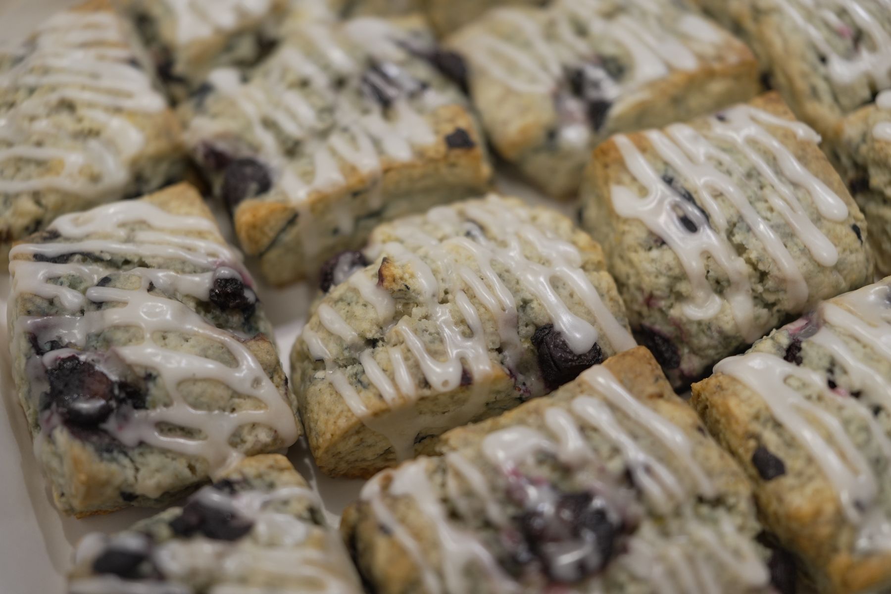 A tray of blueberry scones, each finished with a lemon glaze drizzle.